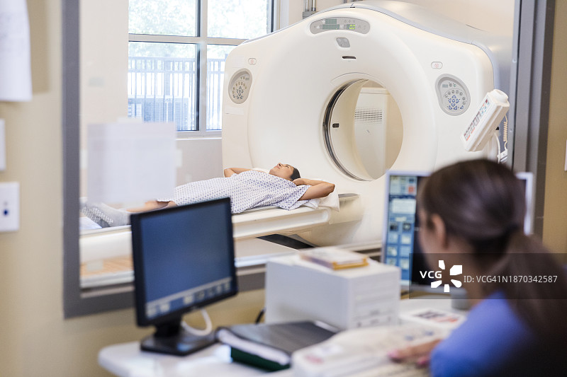 女人躺在CT扫描台上，准备进行CT扫描图片素材