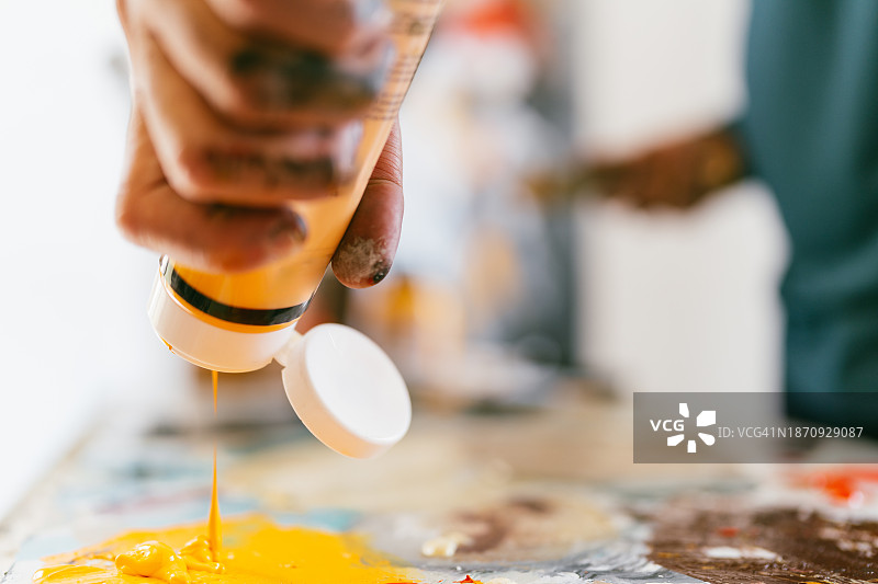艺术家在调色板上倾倒黄色颜料图片素材