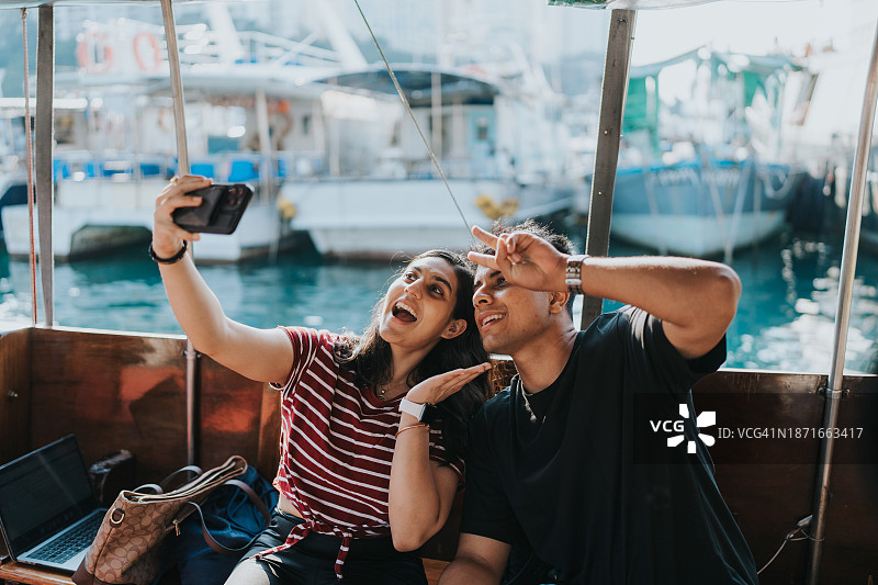 两名印度游客在舢板船上自拍图片素材