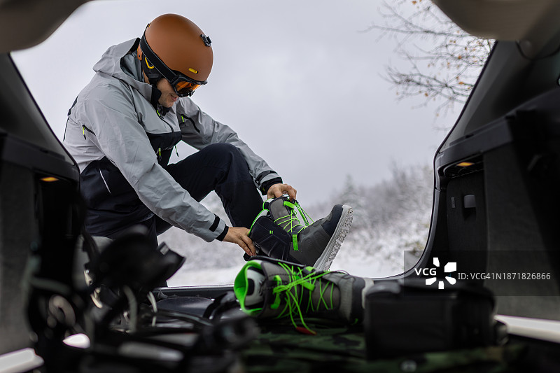 男人在后备箱里穿滑雪靴准备滑雪图片素材