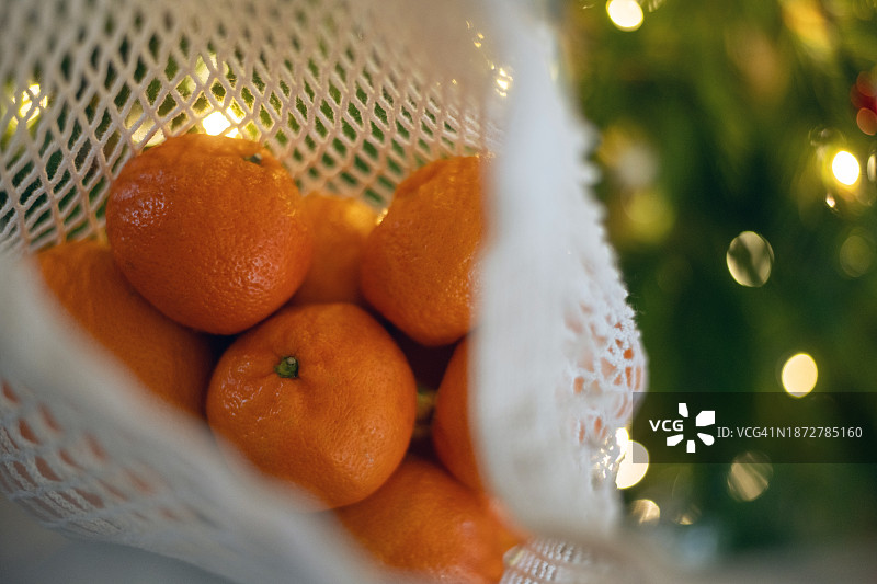圣诞树背景下的环保袋装橘子图片素材