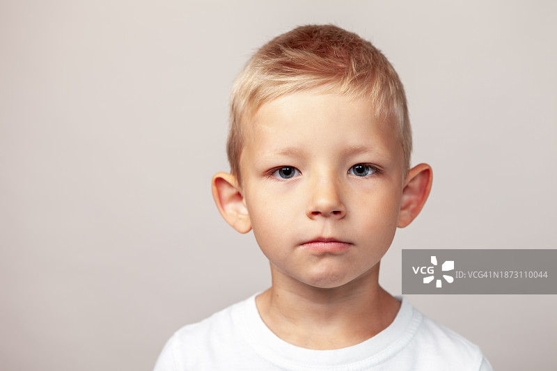 5岁男孩在米色背景下的特写棚拍肖像图片素材
