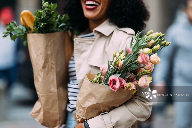 快乐的购物狂欢：容光焕发的女人带着食品和鲜花图片素材