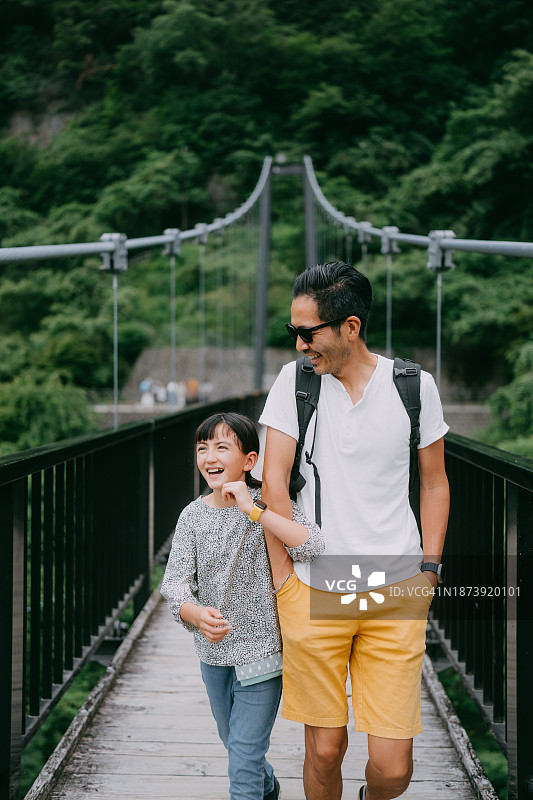 快乐的父亲和女儿在峡谷桥上散步图片素材