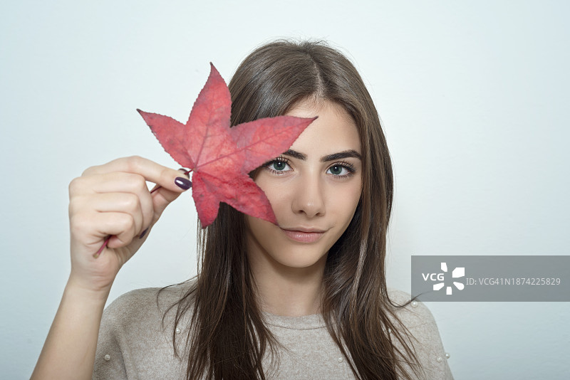 女人拿着一片秋叶挡住眼睛图片素材