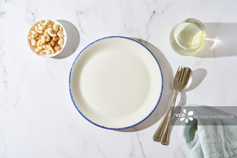 干净的白色餐盘、水杯、叉子和勺子，白色石桌，留白区域图片素材