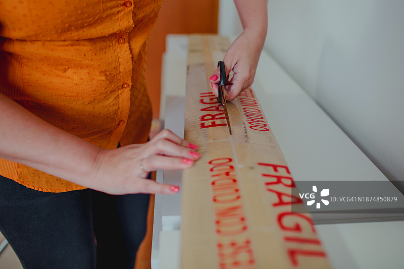 涂有指甲油的女人用剪刀打开纸板箱图片素材