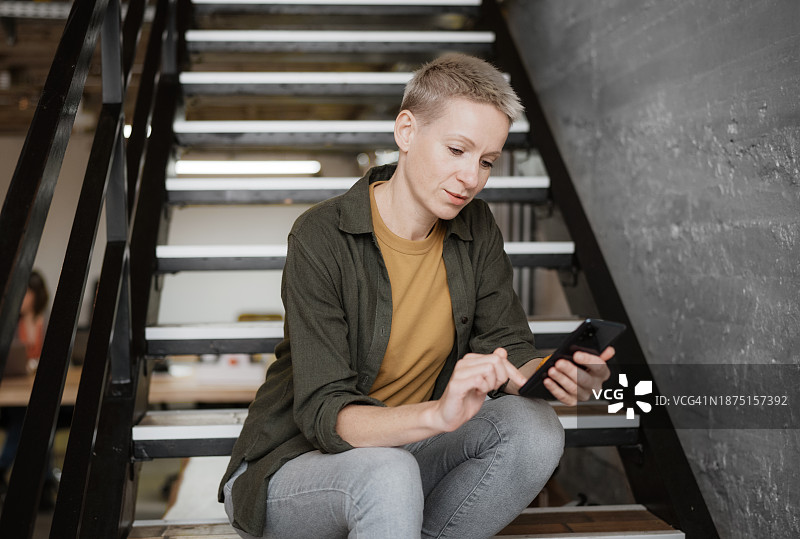 在共享办公室内使用手机的现代女商人图片素材