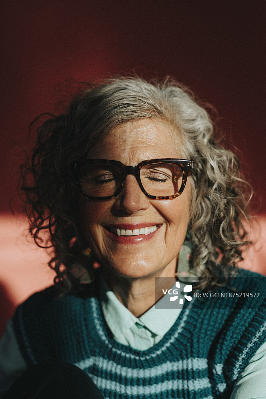 在阳光下闭眼微笑的老年妇女图片素材