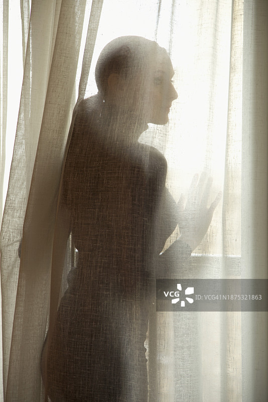 半透明窗帘后女人的侧面剪影图片素材
