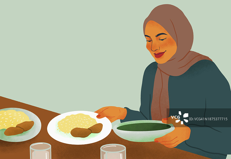 戴着头巾在餐桌旁享受晚餐的微笑女人图片素材