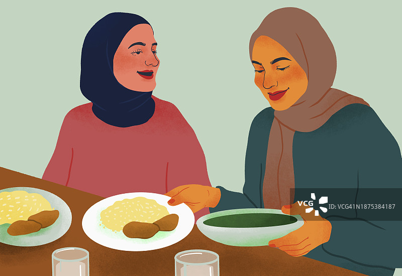 戴着头巾的快乐女性朋友在餐桌旁一起用餐图片素材