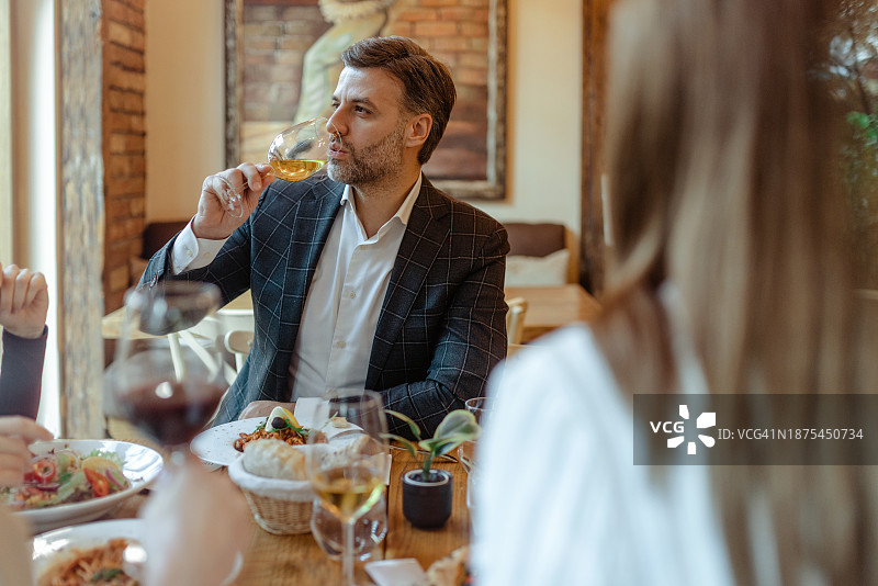 穿商务西装的帅气男人在餐厅品尝白葡萄酒图片素材