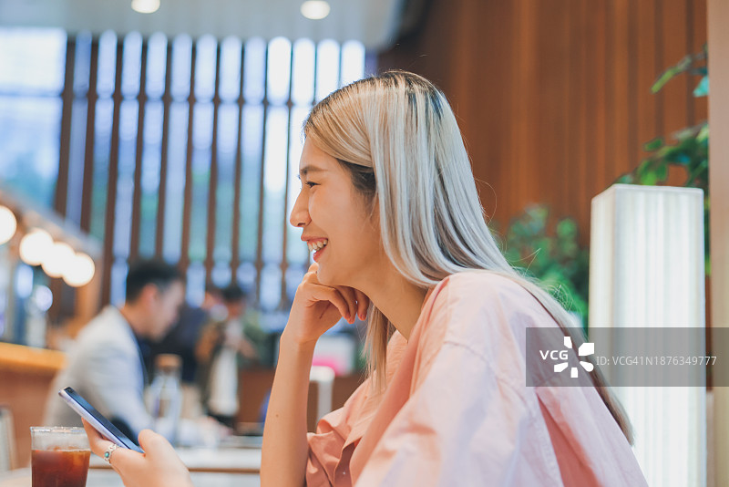 亚洲女性在室内看手机图片素材