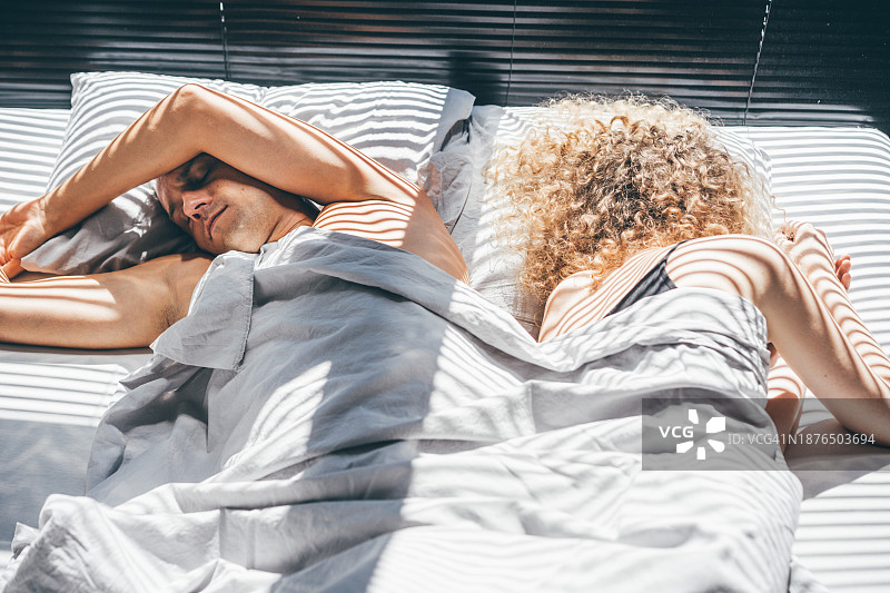 一对中年夫妇背靠背地睡在床上图片素材