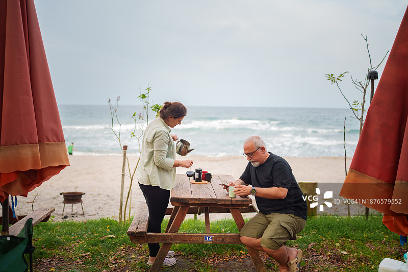 情侣在露营地的野餐桌上准备咖啡图片素材
