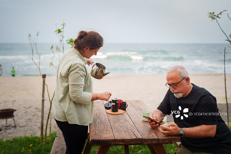情侣在露营地的野餐桌上准备咖啡图片素材