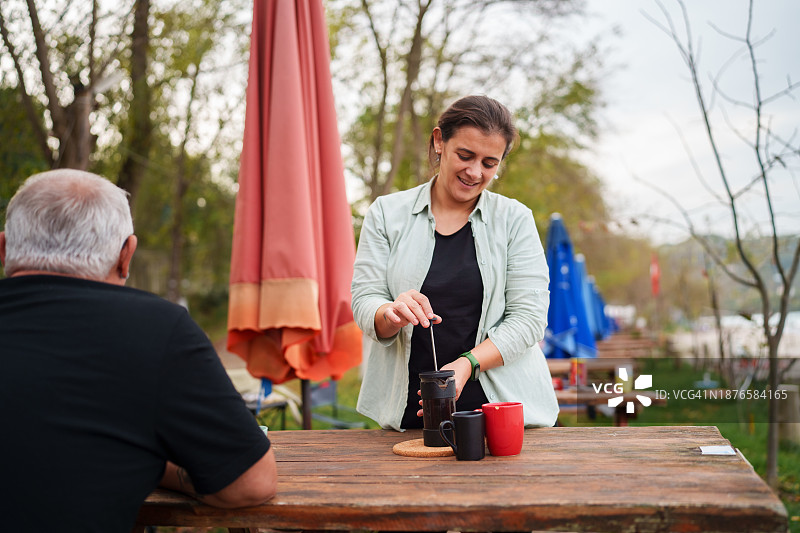情侣在露营地的野餐桌上准备咖啡图片素材