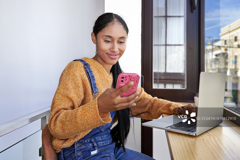 连接笔记本电脑的哥伦比亚拉丁裔数字游民女孩在塞维利亚的共享办公中心咨询其电子商务公司的销售额，并留有复制空间图片素材