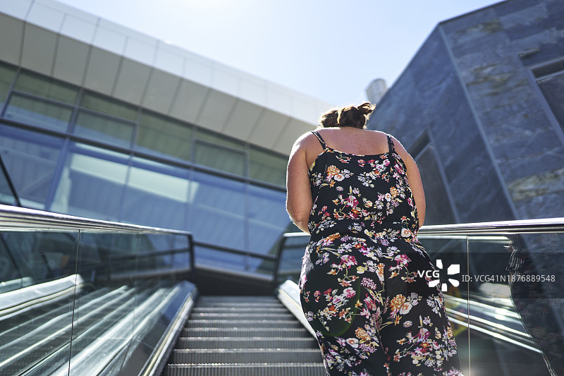 休闲装女游客站在购物中心外的楼梯上的背面图片素材