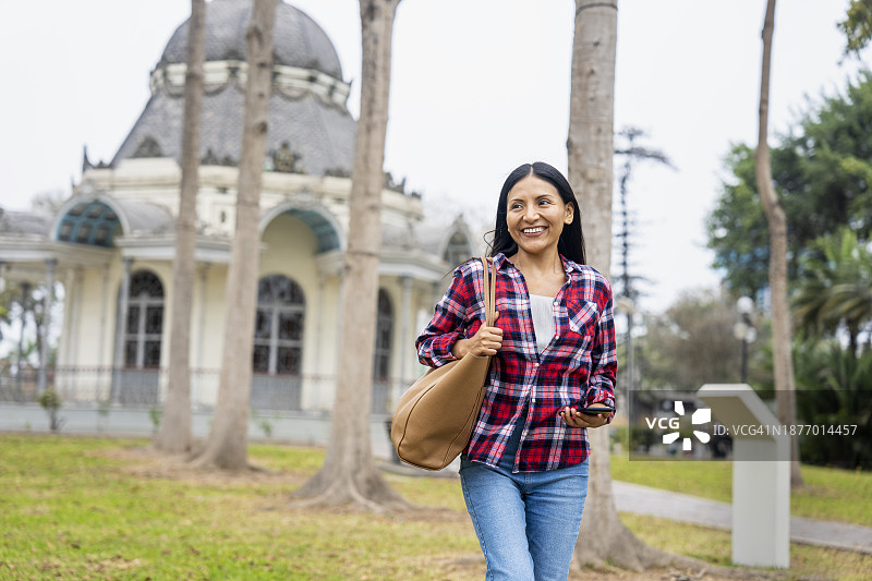 年轻的西班牙裔女子在秘鲁利马展览公园散步图片素材