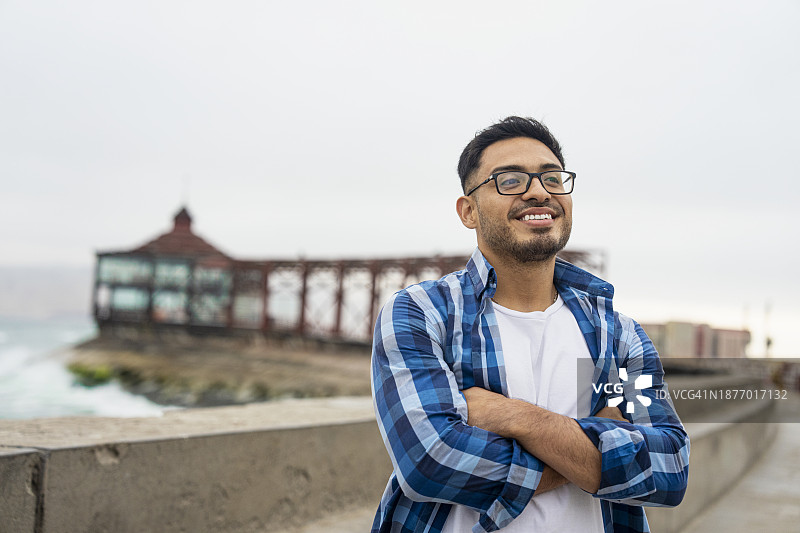 快乐的年轻拉丁美洲男子沿着秘鲁卡亚俄海滩的海岸线行走图片素材