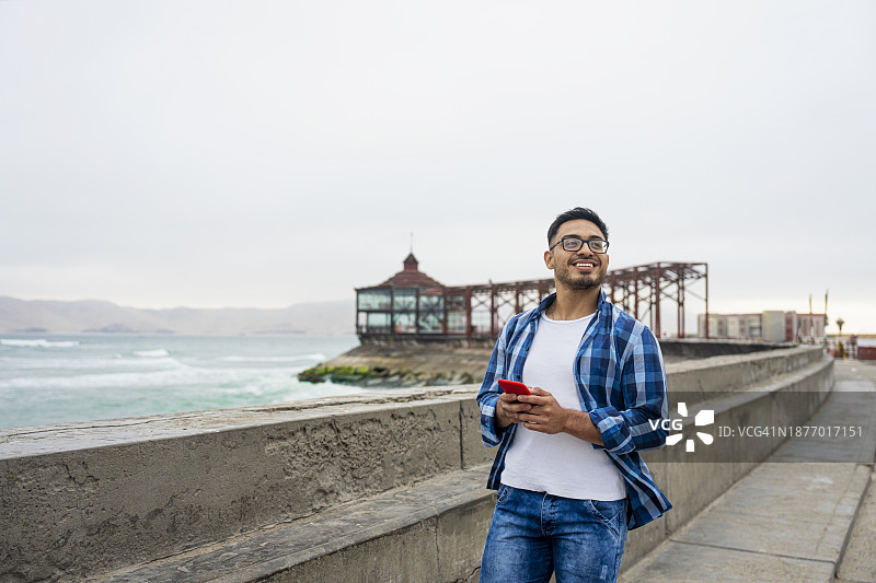 年轻的拉美裔男子在秘鲁卡亚俄海滩观光的半身照图片素材