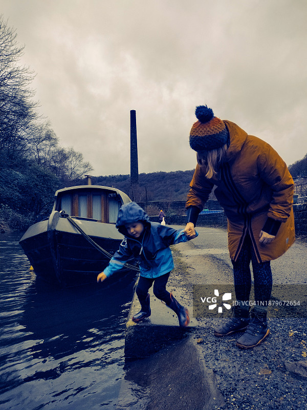 母子在约克郡赫布登布里奇的卡尔德运河上玩水，船屋就在旁边图片素材