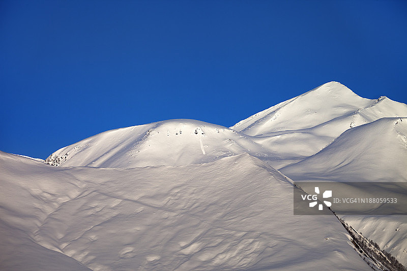 晴朗冬日早晨的野外雪坡和蓝色晴空图片素材