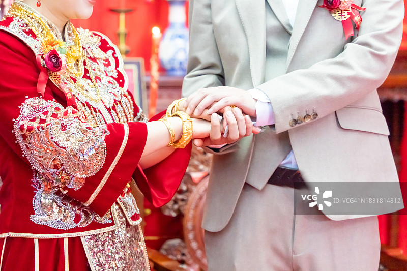 传统中式婚礼上，新娘和新郎紧握双手图片素材