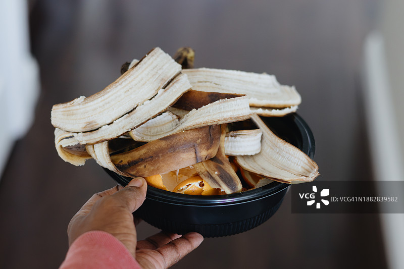 女人拿着装有食物垃圾的容器准备堆肥图片素材