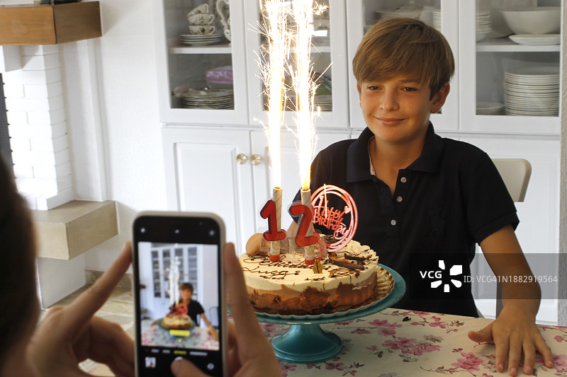 女人在生日时使用手机为孩子拍照图片素材