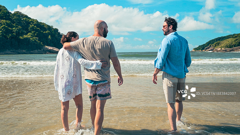 朋友们在沙滩上散步，享受海水图片素材