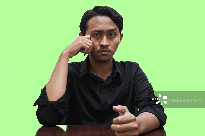 面带怒容的年轻男人坐在绿幕前图片素材