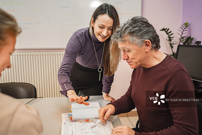女教师在语言学校帮助年长学生学习图片素材