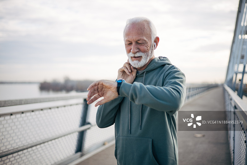 年长的男人测量颈动脉心率，并查看手表图片素材