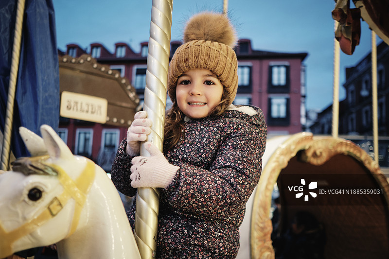 在旋转木马上骑马的微笑女孩图片素材