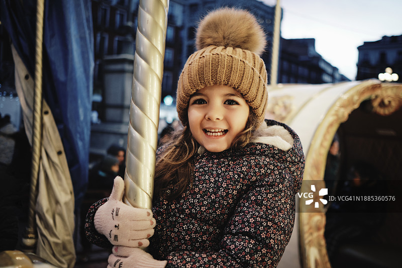 女孩在圣诞市场骑旋转木马图片素材