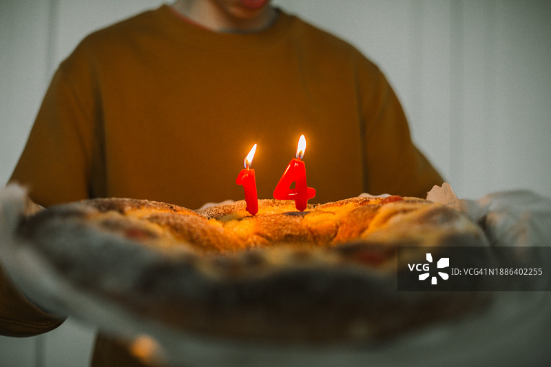 14岁男孩吹灭生日蛋糕上的蜡烛图片素材