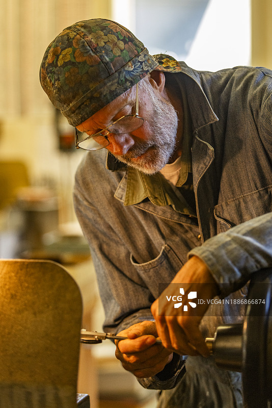 年长的工匠在车间使用电动工具进行木材和金属工艺图片素材