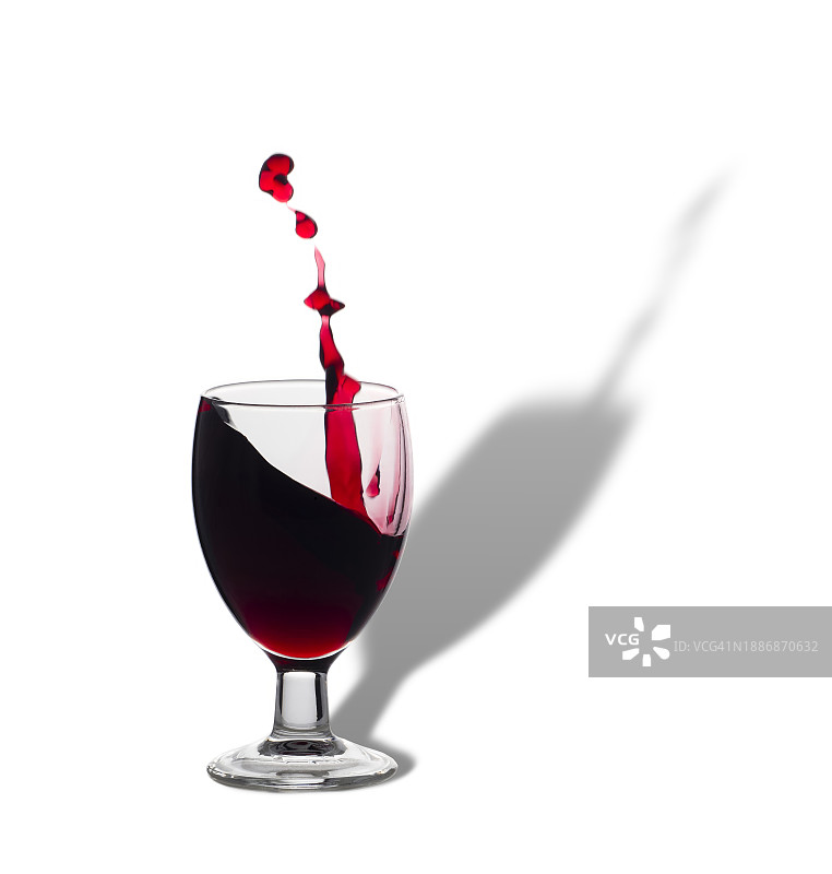 白色背景下带有飞溅水花的红酒杯图片素材