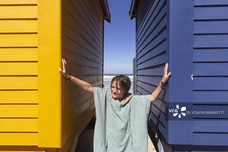 在穆伊曾贝格海滩，一个男孩（10-11岁）在色彩鲜艳的沙滩小屋前摆姿势图片素材