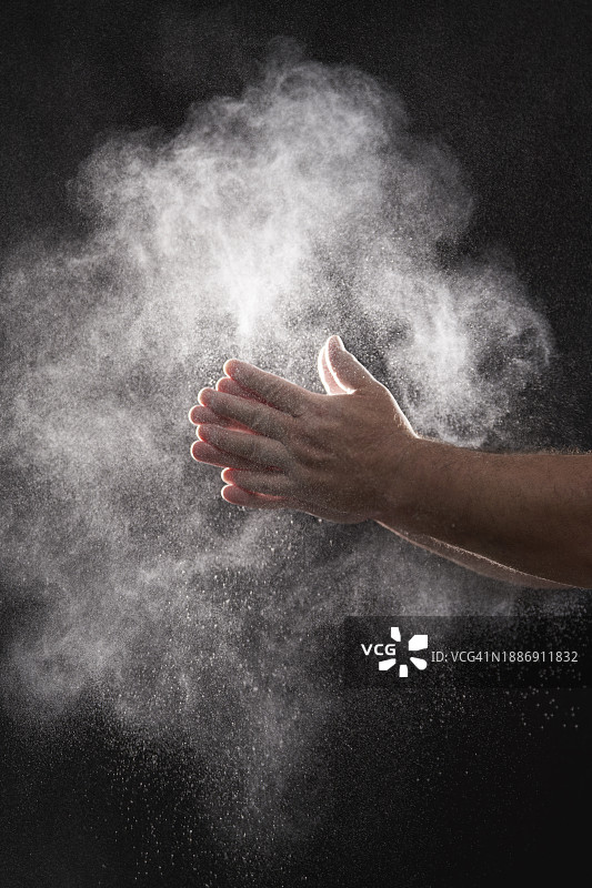 面包师在黑色背景下掸掉手上的面粉图片素材