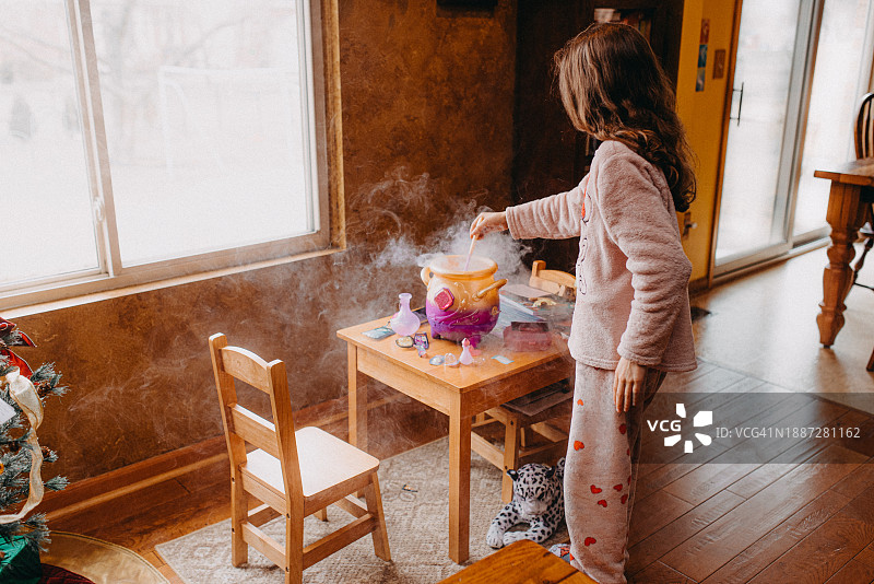 在玩具大锅里混合药水的小女孩图片素材