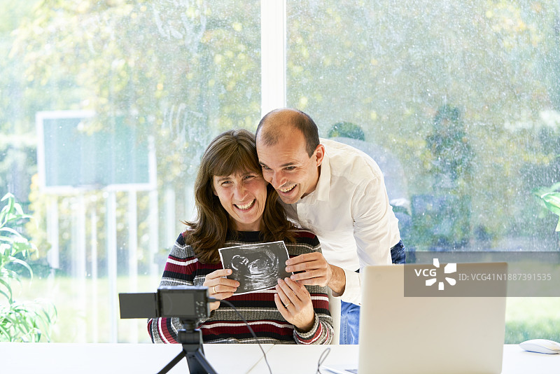 父母在家中向家人展示怀孕超声波视频通话图片素材