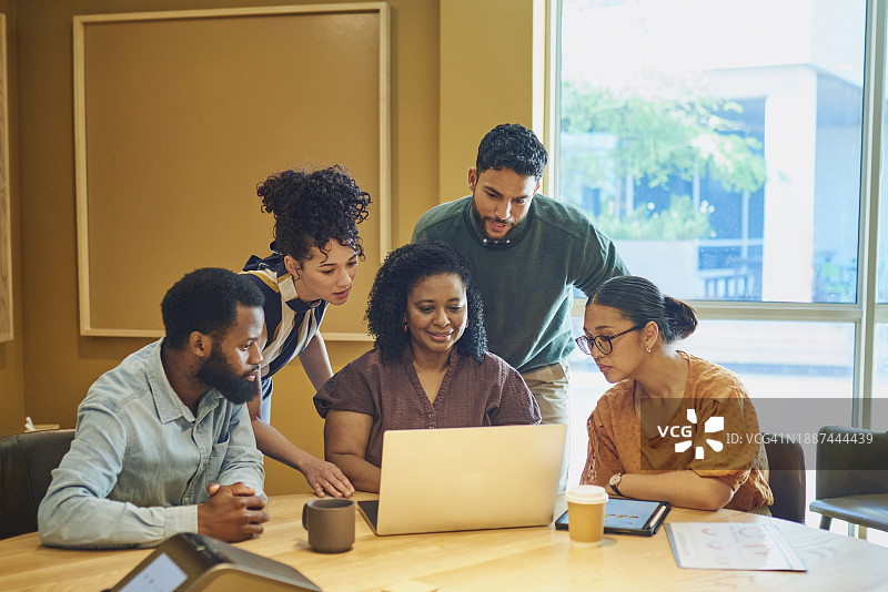 同事们聚集在现代办公室的笔记本电脑旁图片素材