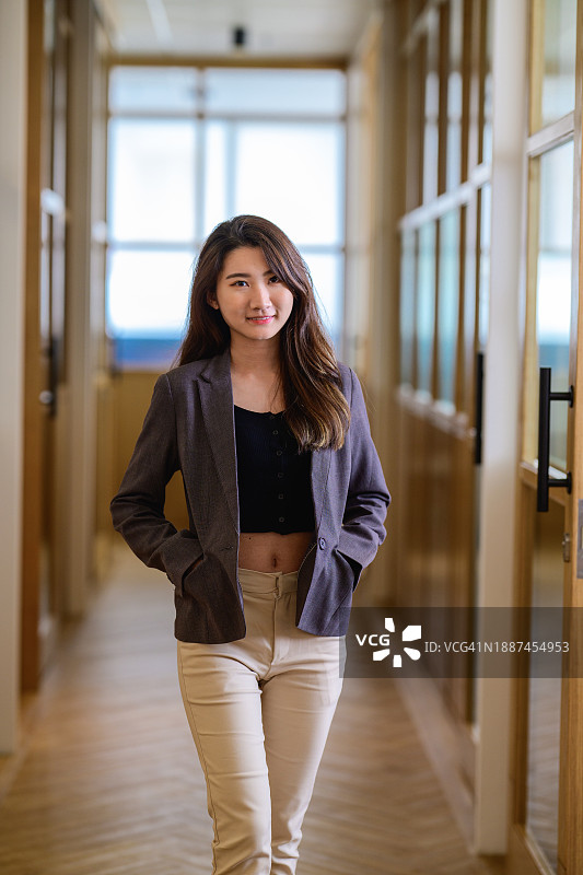 成功的年轻亚洲女高管在办公室走廊里图片素材