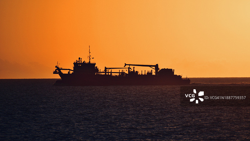 佛罗里达州巴拿马城海面上船只的橙色天空剪影，美国图片素材