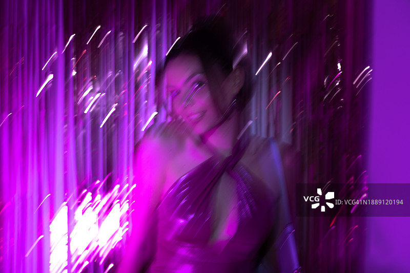 穿着礼服、背景为箔纸派对装饰的年轻女性模糊照片图片素材