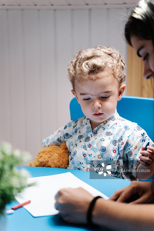 小男孩和妈妈坐在桌旁做作业图片素材